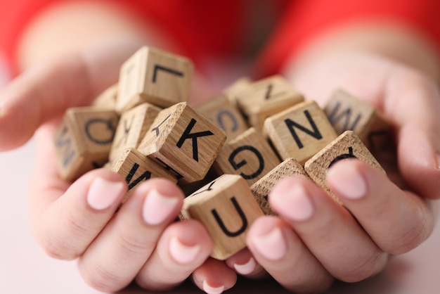 Le mani della donna tengono un mucchio di cubi di legno con lettere da vicino istruzione creatività e apprendimento