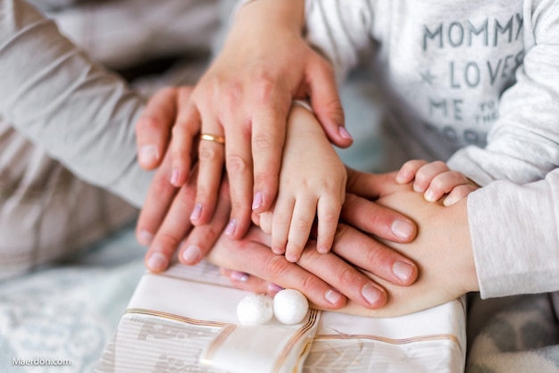 Le mani della famiglia sotto la scatola di Natale