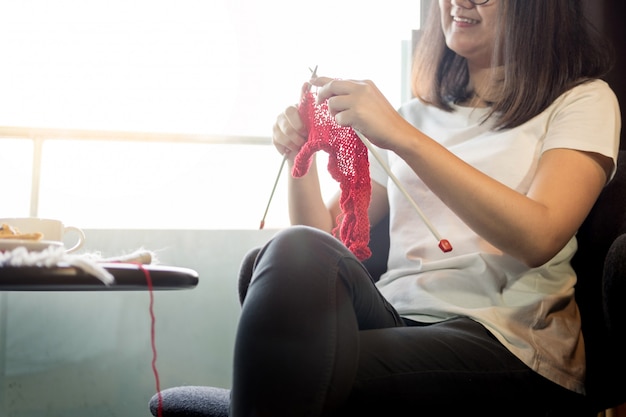 le mani della giovane donna che lavorano a maglia i maglioni caldi. Seduto sulla vecchia poltrona vicino alla finestra