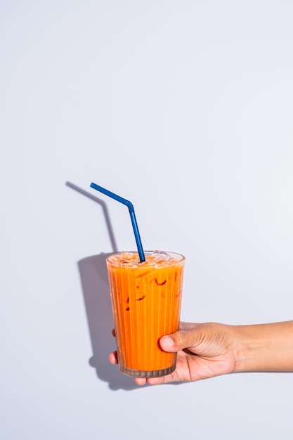 Le mani della giovane donna che tengono il tè al latte freddo su sfondo bianco copiano lo spazio vicino