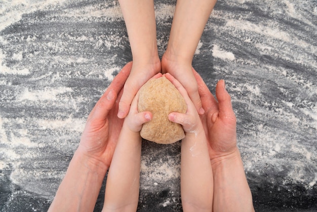 Le mani della madre e di due bambini tengono un pezzo di pasta