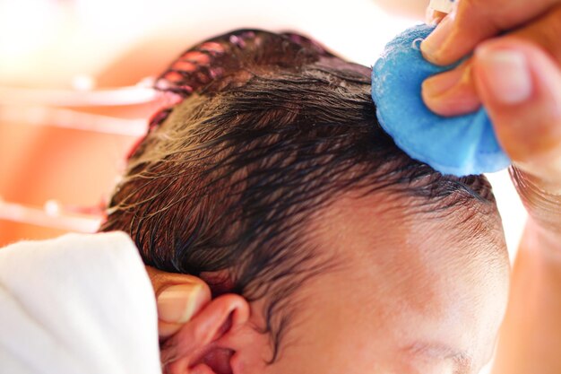 Le mani della madre usano una spugna per fare il bagno e lavare i capelli ai neonati o ai bambini piccoli