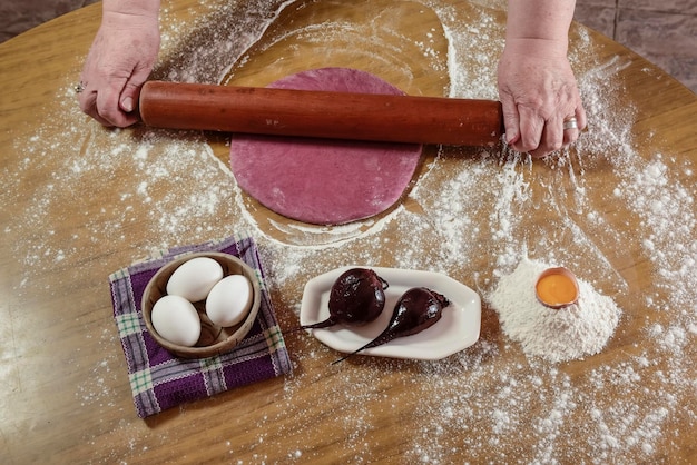 Le mani della nonna che impastano la pasta per le tagliatelle viola