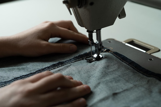 Le mani della ragazza alla macchina da cucire in officina Biancheria da cucire secondo lo schema dell'autore Concetto di atelier di cucito Posto per il testo