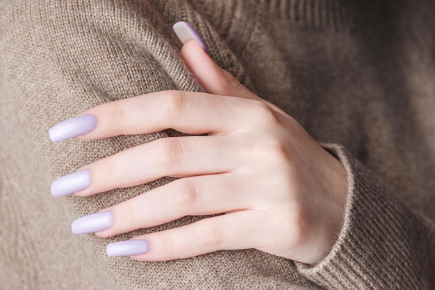 Le mani della ragazza con una morbida manicure viola