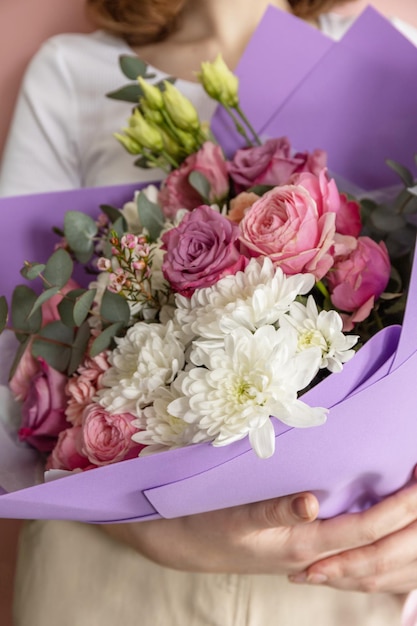 Le mani della ragazza molto carina tengono un bellissimo mazzo di fiori