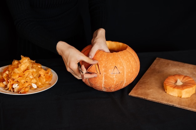 Le mani della ragazza producono una zucca arancione per Halloween