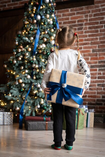 le mani della ragazza tengono il regalo di natale o la confezione regalo decorata per il nuovo anno gioia natale