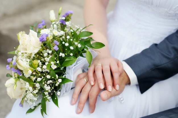 Le mani della sposa e dello sposo con le fedi nuziali