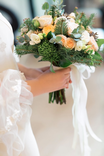 Le mani della sposa tengono un bellissimo bouquet da sposa di rose bianche. fotografia d'arte.