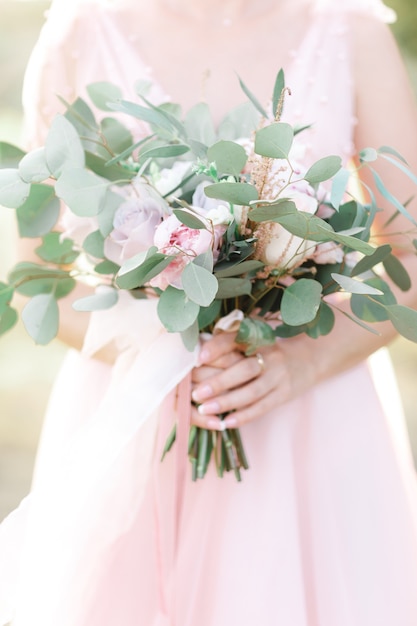 Le mani della sposa tengono un bellissimo bouquet da sposa di rose. fotografia d'arte.