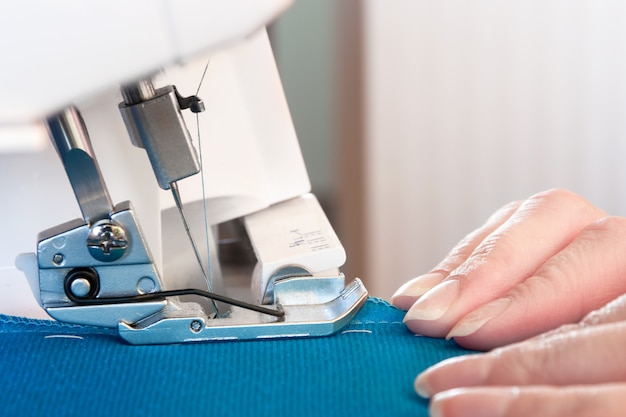 Le mani delle donne al lavoro sulla macchina da cucire.