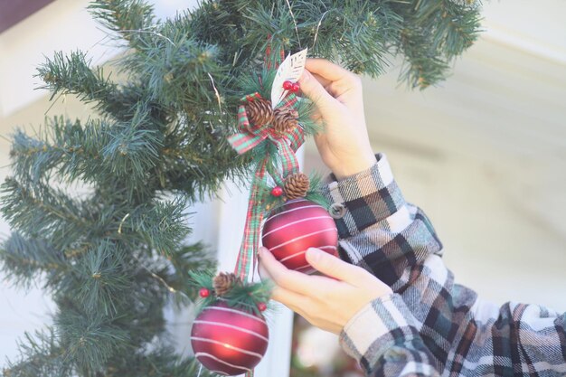 Le mani delle donne appendono un giocattolo su un albero di Natale