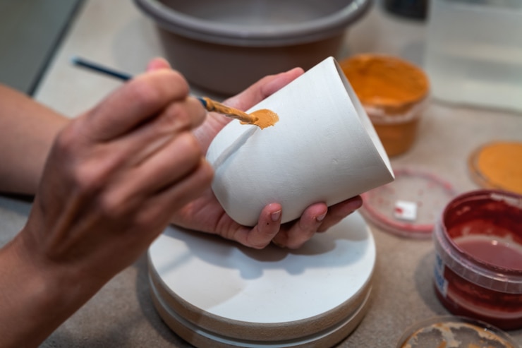 Foto le mani delle donne che dipingono un oggetto di ceramica