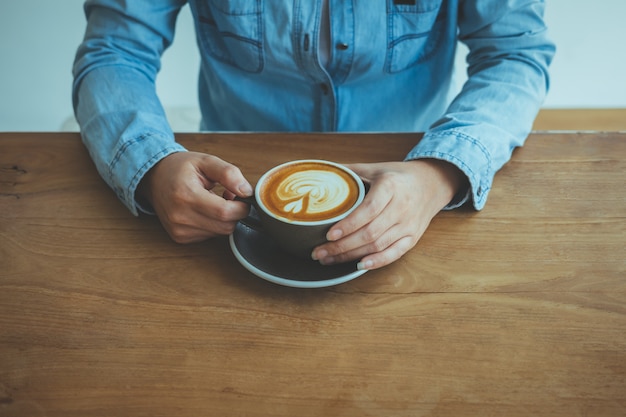 Le mani delle donne che tengono tazza di caffè in caffetteria.