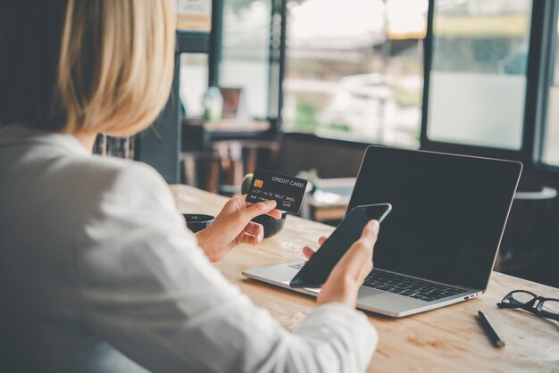 Le mani delle donne che tengono una carta di credito e lavorano sul laptop Pagamento online per lo shopping online