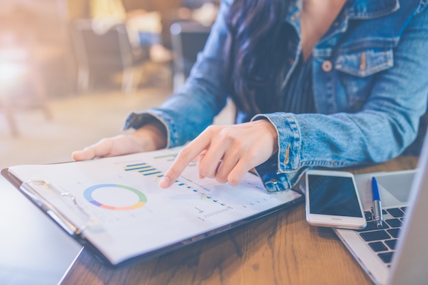 Le mani delle donne che usano smartphone e computer portatili.