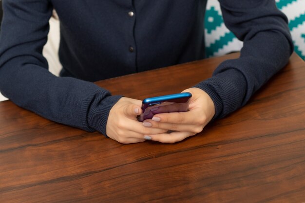 Le mani delle donne con uno smartphone al tavolo in un caffè