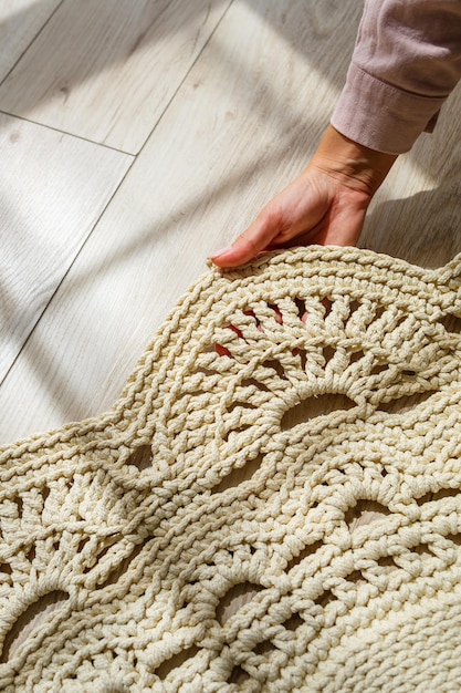 Le mani delle donne giacciono su un plaid di lana a maglia grezza su un pavimento in legno vista dall'alto Tappeto fatto a mano