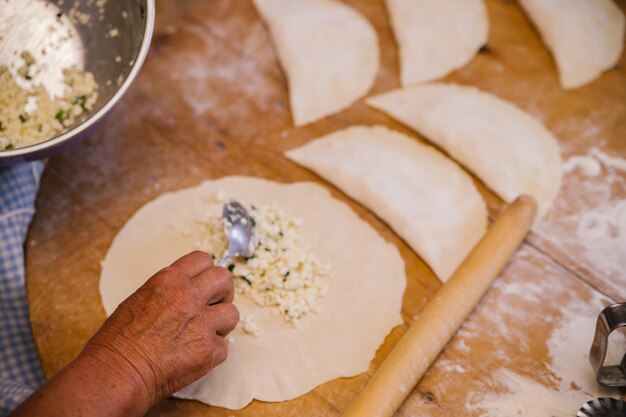 Le mani delle donne nel processo di cottura di kutaba o cheburek carne macinata e cipolle nell'impasto Ricotta e cipolla nell'impasto Cucina greca caucasica tartara azerbaigiana