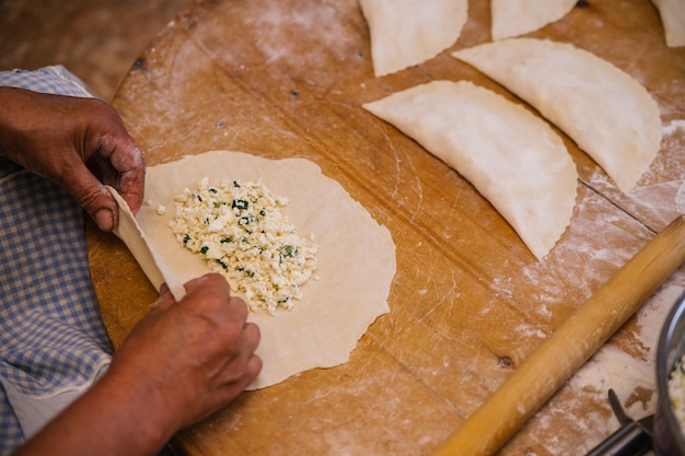 Le mani delle donne nel processo di cottura di kutaba o cheburek carne macinata e cipolle nell'impasto Ricotta e cipolla nell'impasto Cucina greca caucasica tartara azerbaigiana