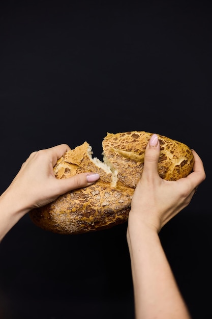 Le mani delle donne rompono un pezzo di pane fresco da vicino