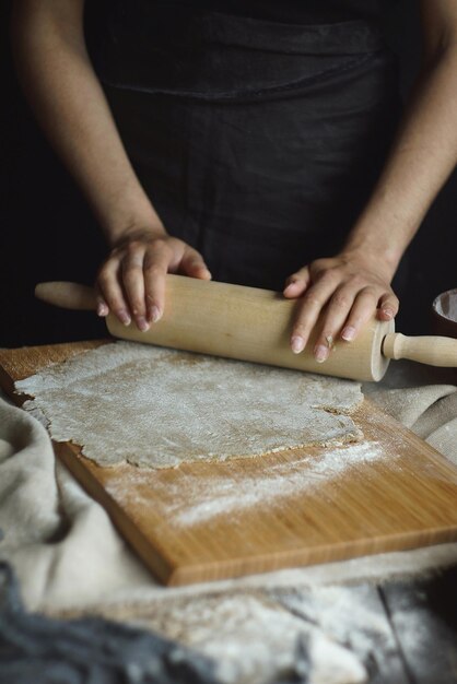 Le mani delle donne stanno preparando tagliatelle crude fatte in casa, Rustico, Messa a fuoco selettiva, Tono scuro atmosferico