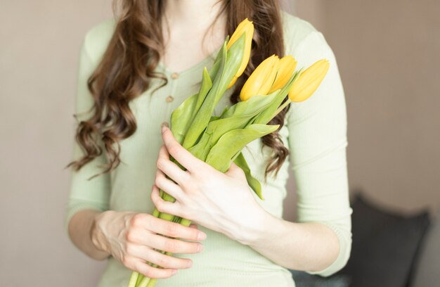 Le mani delle donne stanno tenendo un mazzo di tulipani