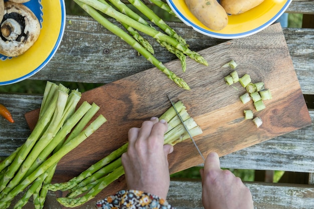 Le mani delle donne tagliano gli asparagi Preparazione per grigliate verdi Piatti vegani