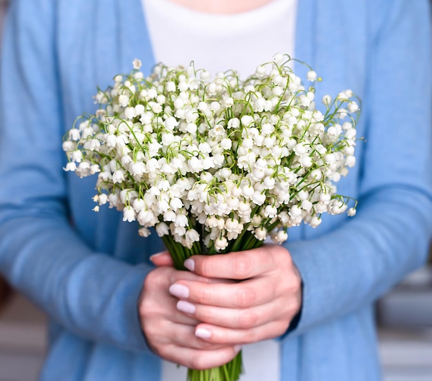 Le mani delle donne tengono il bellissimo bouquet di gigli della valle Focus selettivo