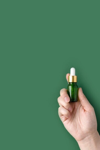 Le mani delle donne tengono una bottiglia con vitamine essenziali e un prebiotico per il trattamento della pelle o dei capelli