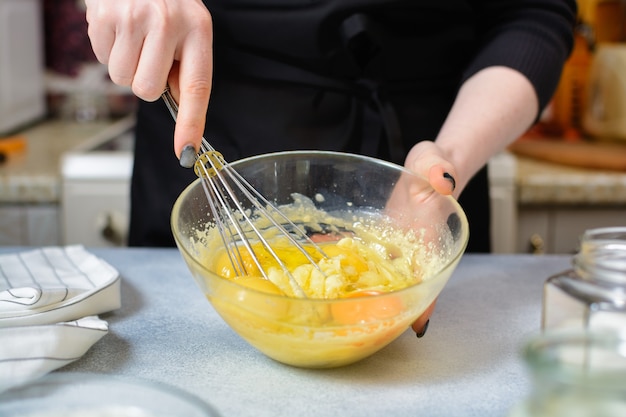 Le mani dello chef hanno sbattuto il tuorlo d'uovo e l'impasto in una ciotola di vetro