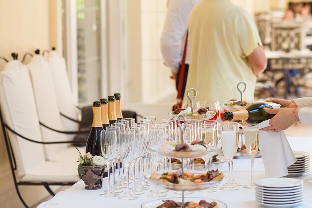 Le mani dello steward riempiono i bicchieri di champagne alla reception