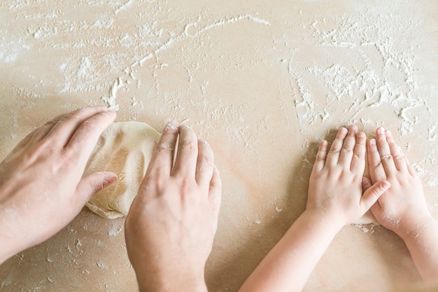 Le mani di bambini e papà producono un impasto crudo