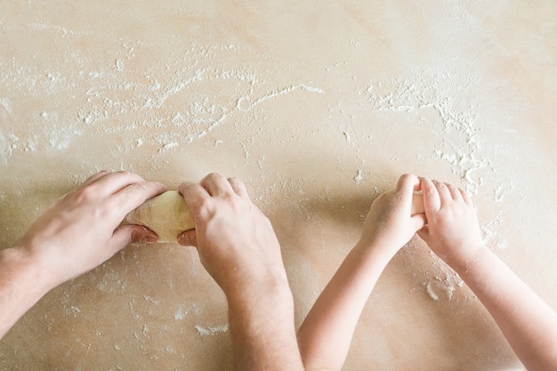 Le mani di bambini e papà producono un impasto crudo