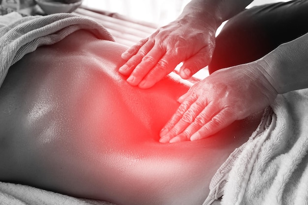 Le mani di Msseuse mentre lavorano abilmente sullo stomaco di una cliente donna durante un massaggio