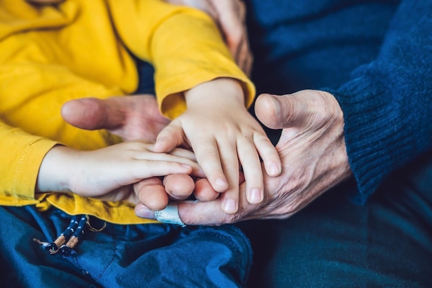 Le mani di un anziano e le mani di un bambino, la continuità delle generazioni, la cura degli anziani.