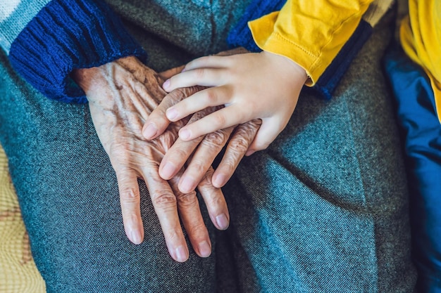 Le mani di un anziano e le mani di un bambino, la continuità delle generazioni, la cura degli anziani