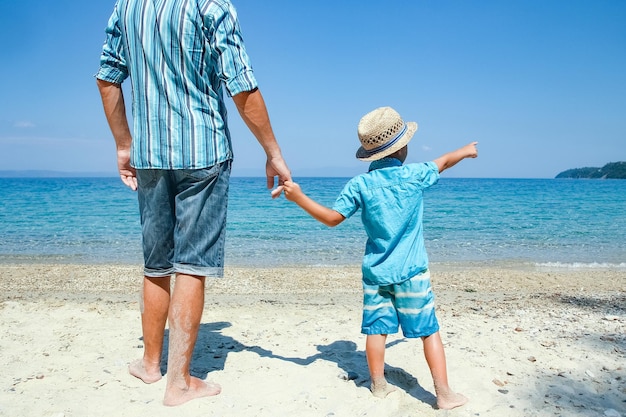 Le mani di un genitore e di un figlio felici in riva al mare nel viaggio nella natura