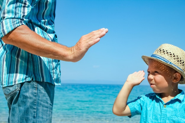 Le mani di un genitore e di un figlio felici in riva al mare nel viaggio nella natura