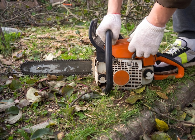 Le mani di un uomo avviano una motosega in giardino