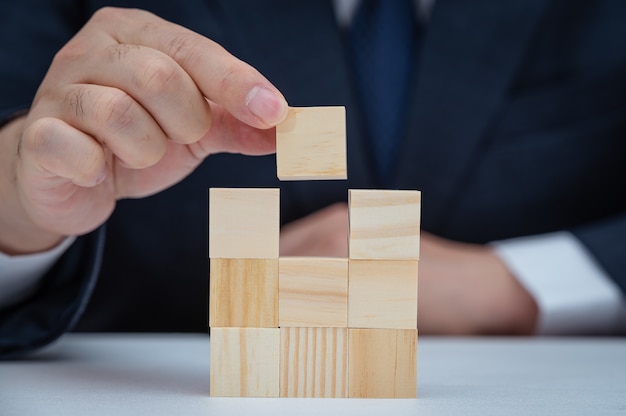 Le mani di un uomo d'affari che sta impilando blocchi di legno. Concetto di affari.