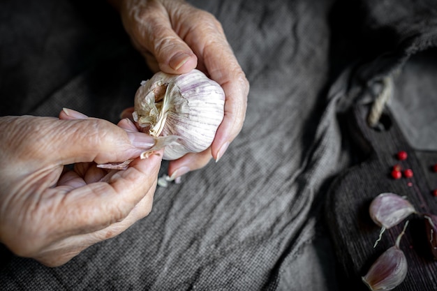 Le mani di una donna anziana sbucciano l'aglio