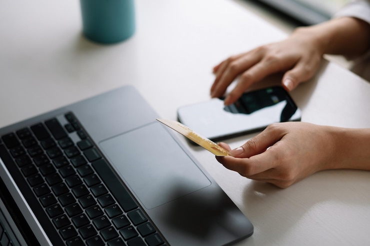 Foto le mani di una donna che tiene in mano una carta di credito e uno smartphone che paga online utilizzando un servizio bancario