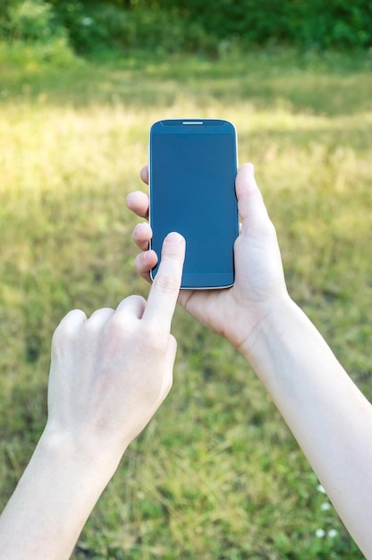 Le mani di una donna che utilizzano uno smartphone all'aperto