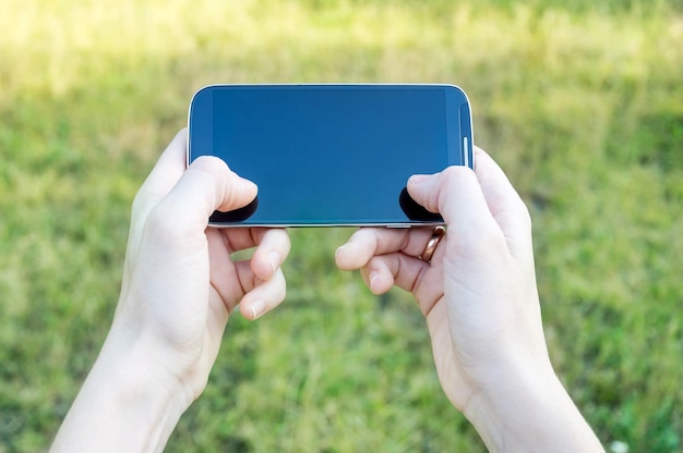 Le mani di una donna che utilizzano uno smartphone all'aperto