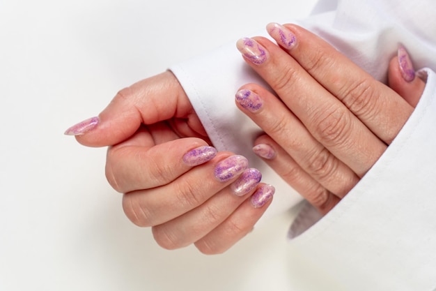 Le mani di una donna con manicure viola sulle unghie