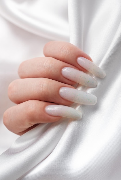 Le mani di una donna con una manicure su di esse le unghie sono dipinte di bianco