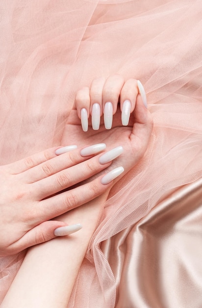 Le mani di una donna con una manicure su di esse le unghie sono dipinte di bianco