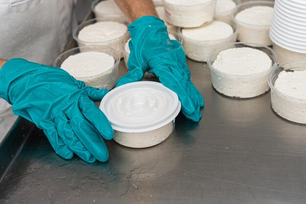 Le mani di una donna confezionano un lavoro di formaggio fresco